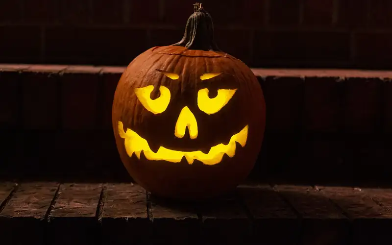 A glowing carved jack-o'-lantern on a brick ledge at night