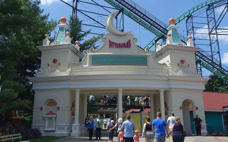 The white entrance gate at Kennywood amusement park with roller coaster track behind it